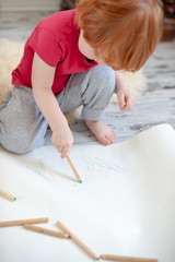 The boy draws scribbles with colored pencils