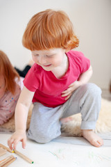 A boy smiling stretches out behind a colored pencil