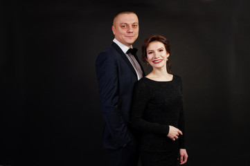 Elegance woman in black evening dress with man in suit posed on studio isolated on black. Duet couple of two.