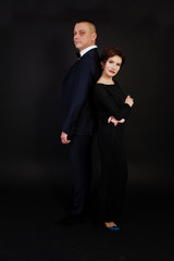 Elegance woman in black evening dress with man in suit posed on studio isolated on black. Duet couple of two.