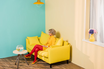 woman in bright retro clothing resting on sofa at colorful apartment, doll house concept