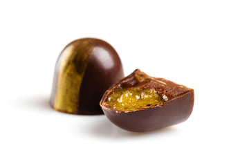 Cut luxury handmade bonbons with chocolate ganache and citrus fruit jelly filling isolated on white...