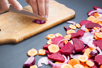 Closeup on man cutting red onion. Male hands chopped fresh red onion on wooden board.