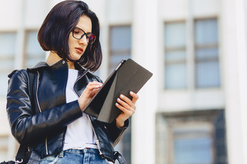 girl in glasses with tablet on background of building