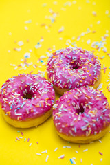 pink donuts with sprinkles on yellow background 