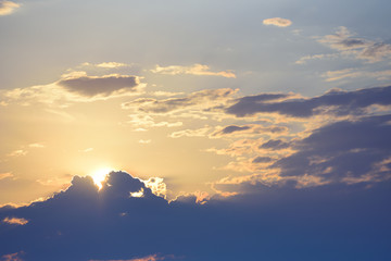 Evening sky with a leaving sun and hiding behind clouds