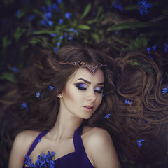 Elf girl with long hair in the tiara rests in spring forest blue forest flowers. Girl Princess dreams. © moredix