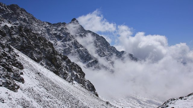 Clouds creeping over a mountain peak. View from the Laurebina La mountain pass, Nepal. Spring morning in the Himalayas.