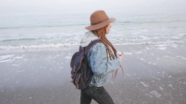 Young woman with corgi dog posing on the beach, girl with dreadlocks and hat with pet 