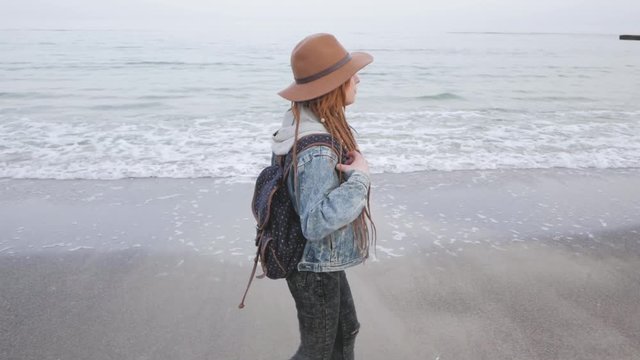 Young woman with corgi dog posing on the beach, girl with dreadlocks and hat with pet 