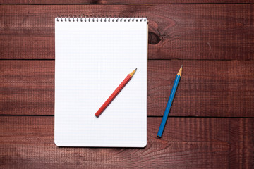 Bright colorful pencils next to a blank sheet of paper. School supplies stationery on a wooden texture table. Trendy minimalism. Concept back to school. Top view