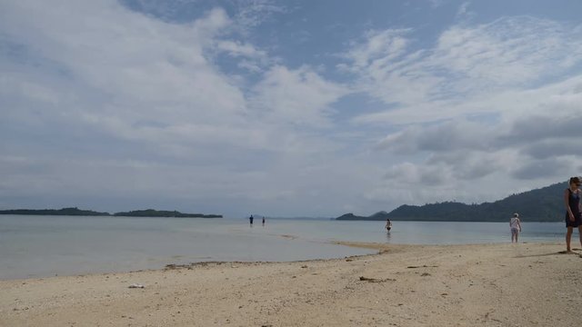 Tourists walk on starfish island on small beach by boat
