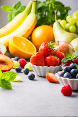 Fototapeta na wymiar Fresh assorted fruits and berries on light gray background. Colorful clean and healthy eating. Detox food. Copy space.