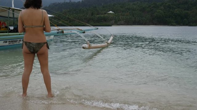Sexy woman take mobile phote from boat at Port Barton island, Philippines