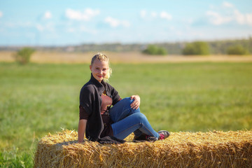 Naklejka na ściany i meble beautiful girl sits on a haystack 