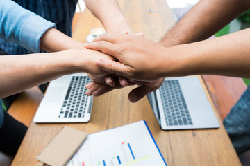 Close-up of business partners making pile of hands in meeting room, teamwork power successful...