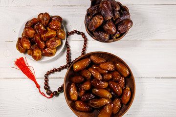 Dates fruit and rosary on white wooden table. Top view