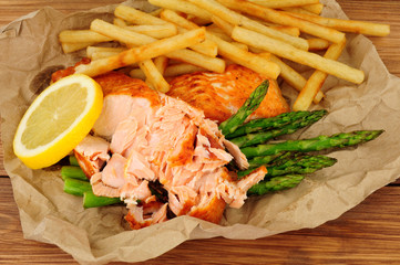 Grilled salmon fillet and French Fries meal with asparagus on a wooden background