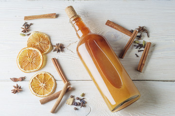 Bottle of fresh alcoholic tincture with cinnamon, pepper, orange on the bar table