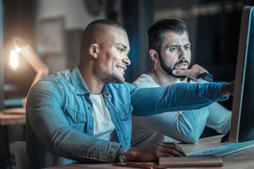 Programming land. Doubtful energetic two colleagues working together while chatting and man stretching hand