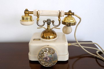 Sehr altes weiß-goldenes Telefon mit drehbarer, verzierter Wählscheibe, Hörer und Schnur