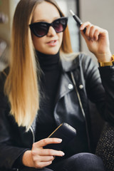 Girl sit in caffee place and smoke electronic cigarette wear glasses