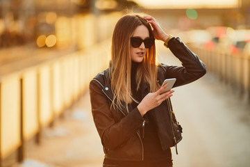 Young girl stand on the street place wear glasses, talk at her phone and smile