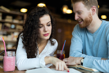 Young students spending time in coffee shop reading books