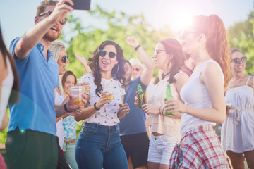 Group of people dancing and taking selfie at the outdoor party/music festival