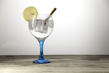 gin tonic on blue glass with  lemon slice and cinnamon