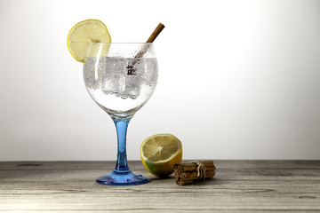 gin tonic on blue glass with lemon and stick cinnamon