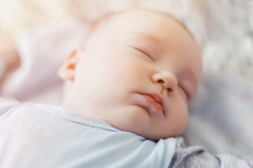Peaceful baby lying on a bed while sleeping in a bright room