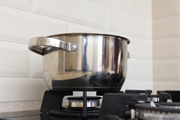 A beautiful shiny saucepan stands on the gas stove in the kitchen