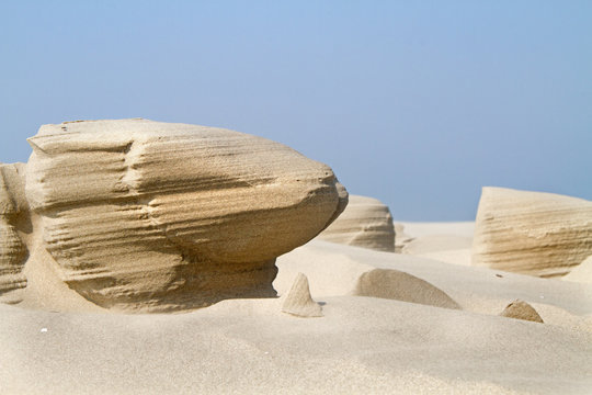 Wind erosion forms strange sculptures in the sand of a beach