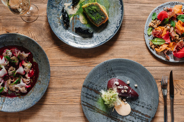 top view of delicious dishes and glass of wine on wooden table