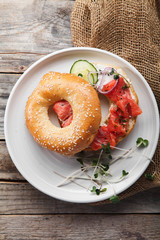 Bagels with salmon fish, cream cheese, cucumber and fresh radish slices on rustic gray wooden background