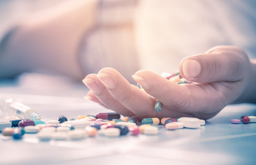 Overdose - close up of pills and addict. woman taking medicine overdose and lying on the wooden...