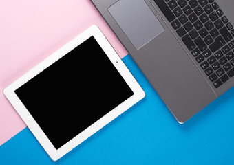 Tablet and laptop on pink and blue background.