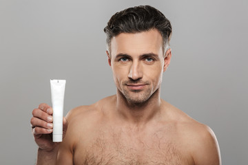 Handsome mature man holding cream. Looking camera.