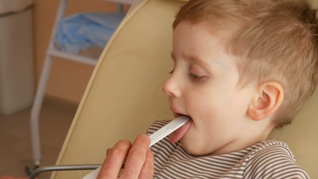 Little Boy Having Throat Examination. male doctor pediatrician, otolaryngologist, inspects a cute little boy's throat. Close up