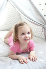 Smiling 2 years little girl in wigwam tent bed at home