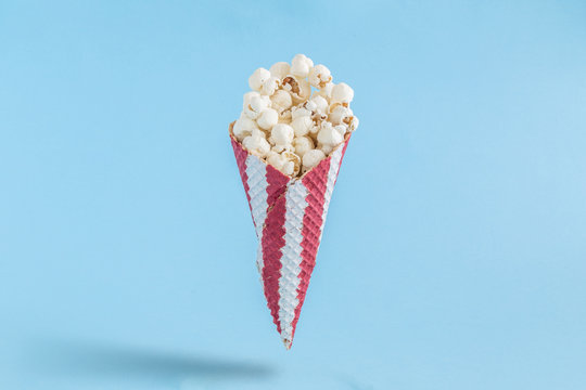Popcorn in cone on blue background minimalistic concept.