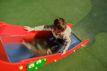 Cute caucasian child boy having fun to play slider in the playground