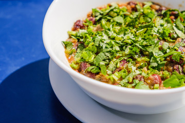 Lobio dish with red beans, spices and herbs. On blue table.