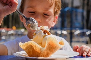 Close-up detail, child eating ice cream. Outdoor at the cafe