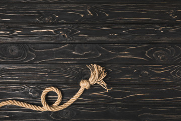 top view of knotted brown nautical rope on dark wooden surface