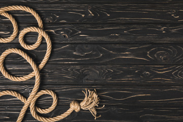top view of knotted brown nautical rope on dark wooden surface