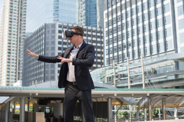 Caucasian Businessman wearing black suit and Virtual Reality Headset (VR) imagine to fighting in the air