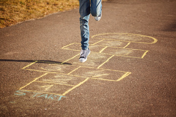 Kids playing hopscotch on playground outdoors. Hopscotch popular street game