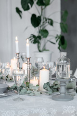Wedding or festive table setting. Plates, wine glasses, candles and cutlery